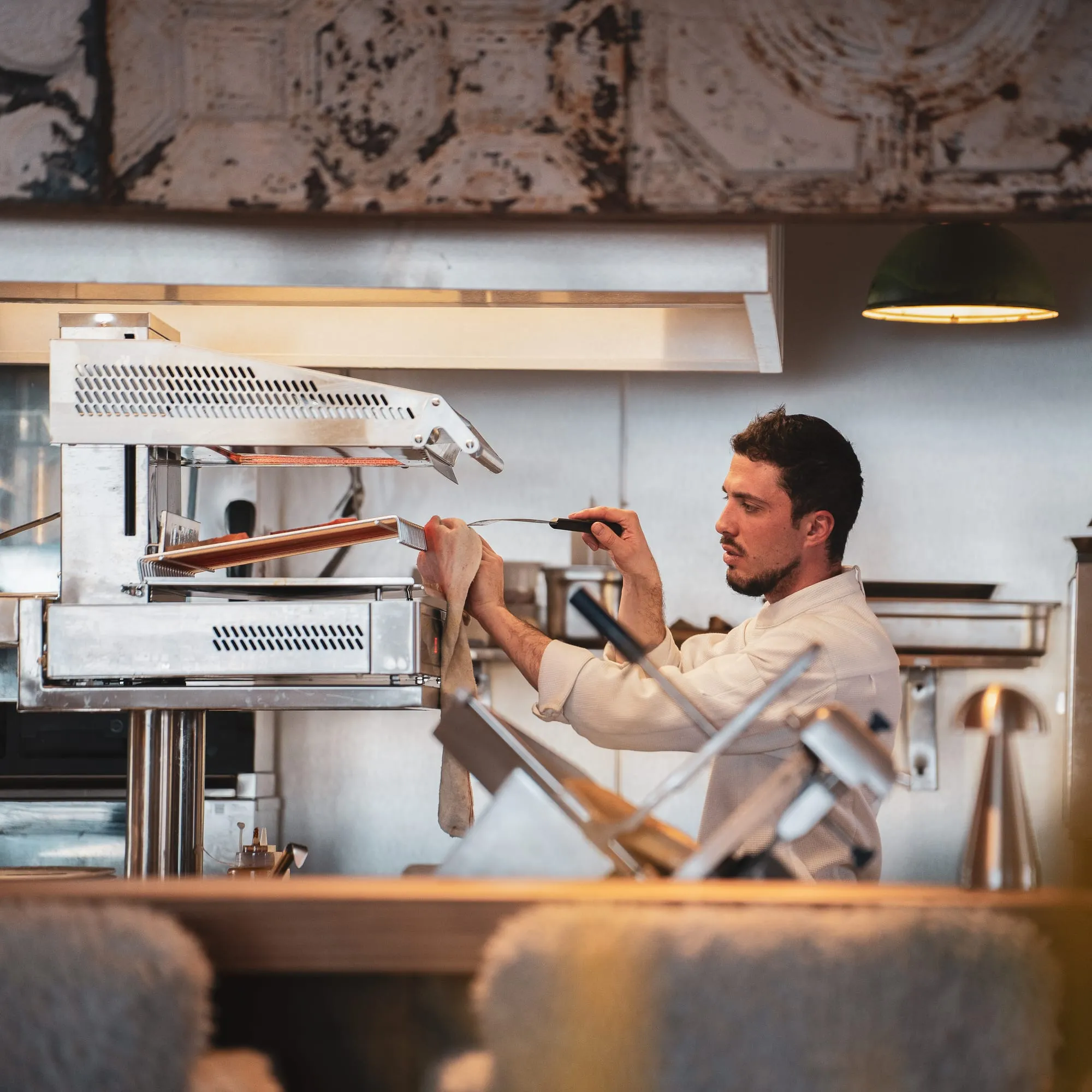 Le chef en veste blanche, en cuisine.