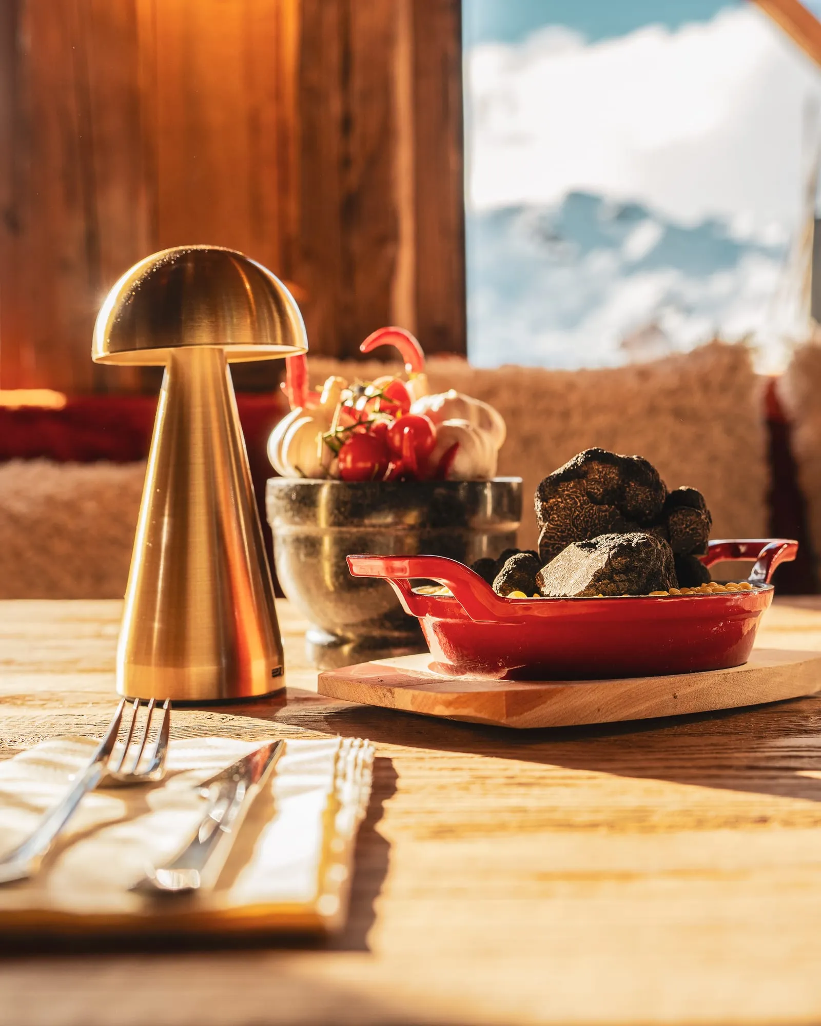 Un gratin doré servi en cocotte rouge, une truffe noire posée dessus.