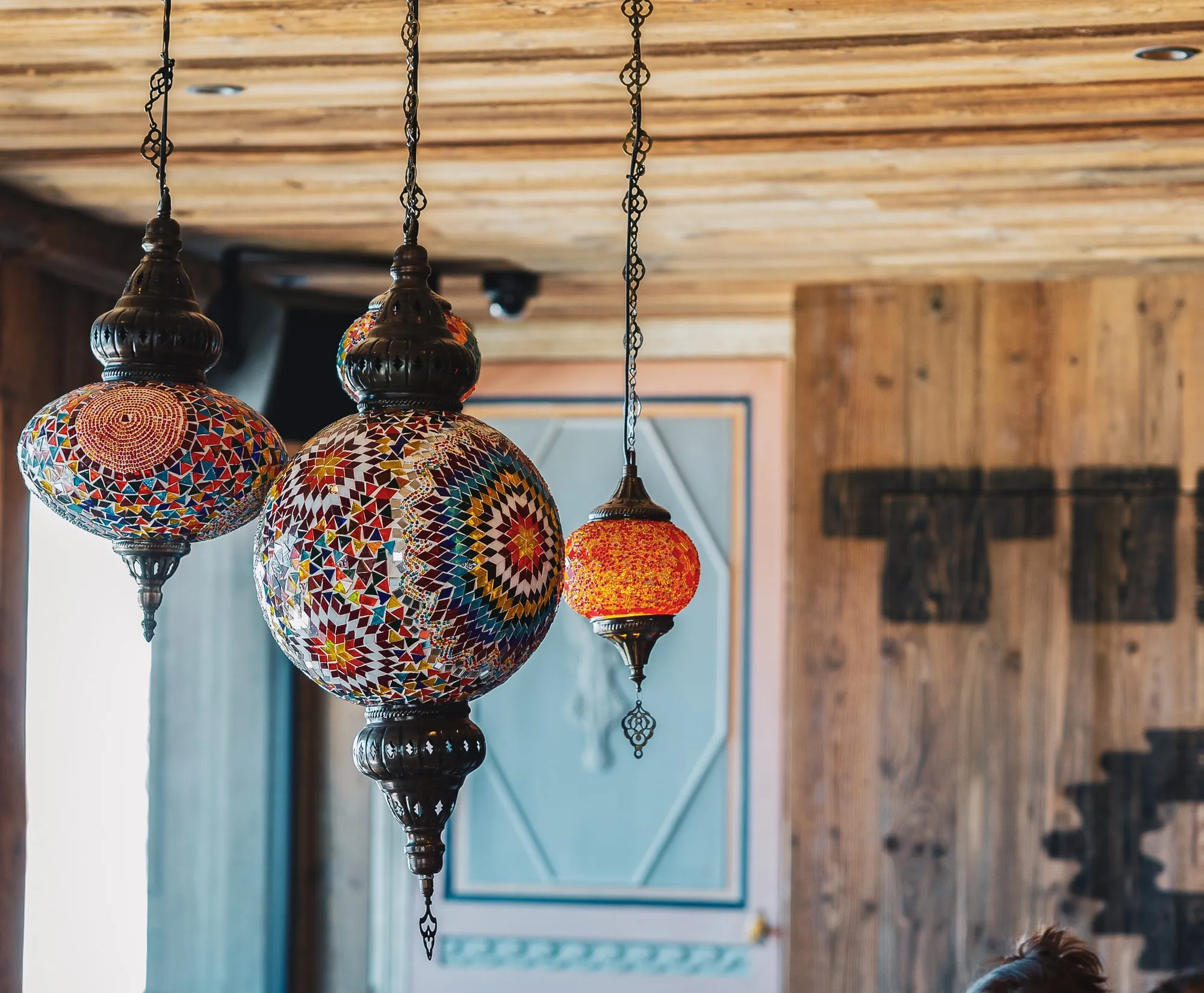 Des lustres en mosaïque de verre coloré suspendus devant les murs de bois.