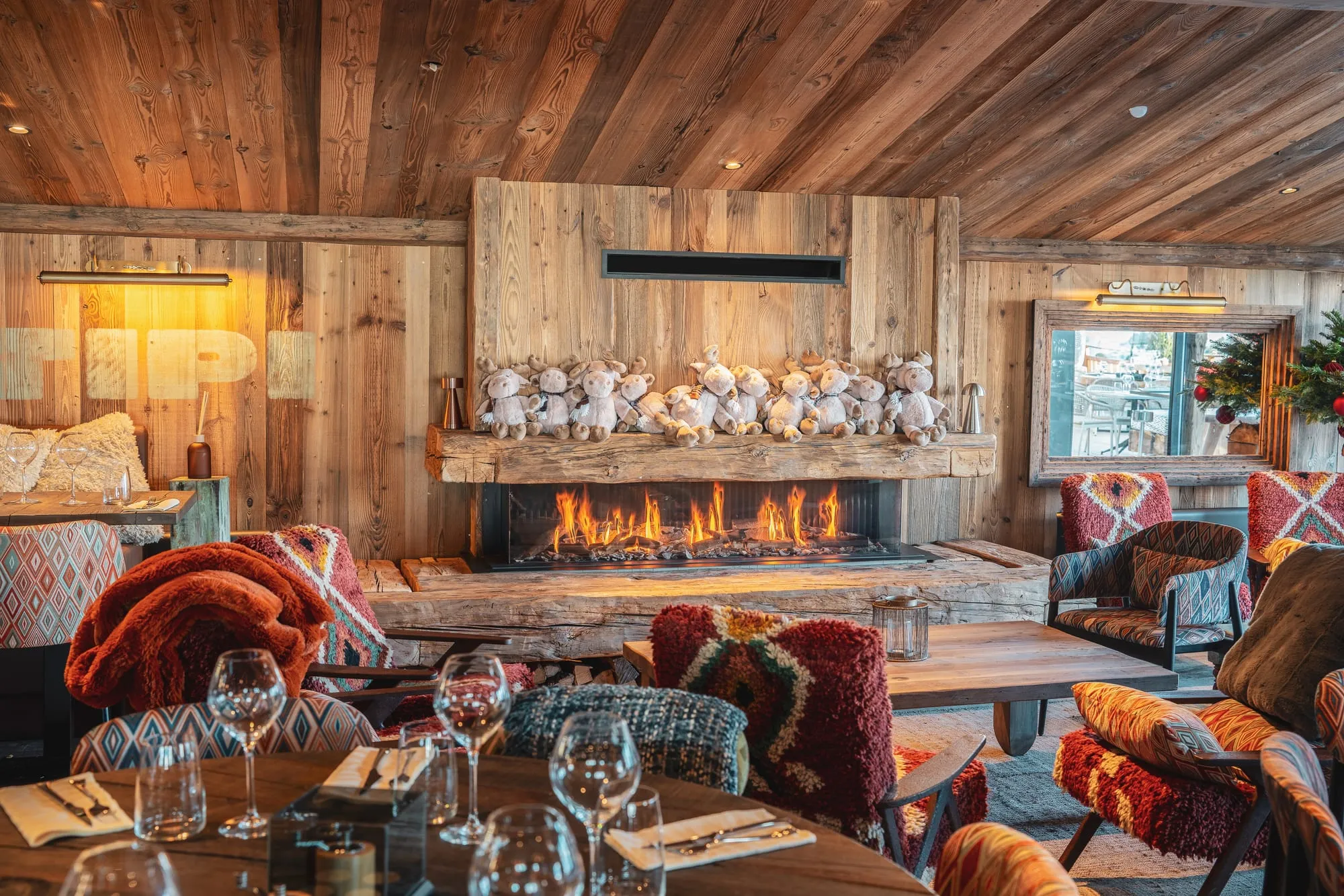 Le salon de Tipi : canapés, coussins et kilims devant la cheminée, une rangée de petits ours au-dessus du feu.