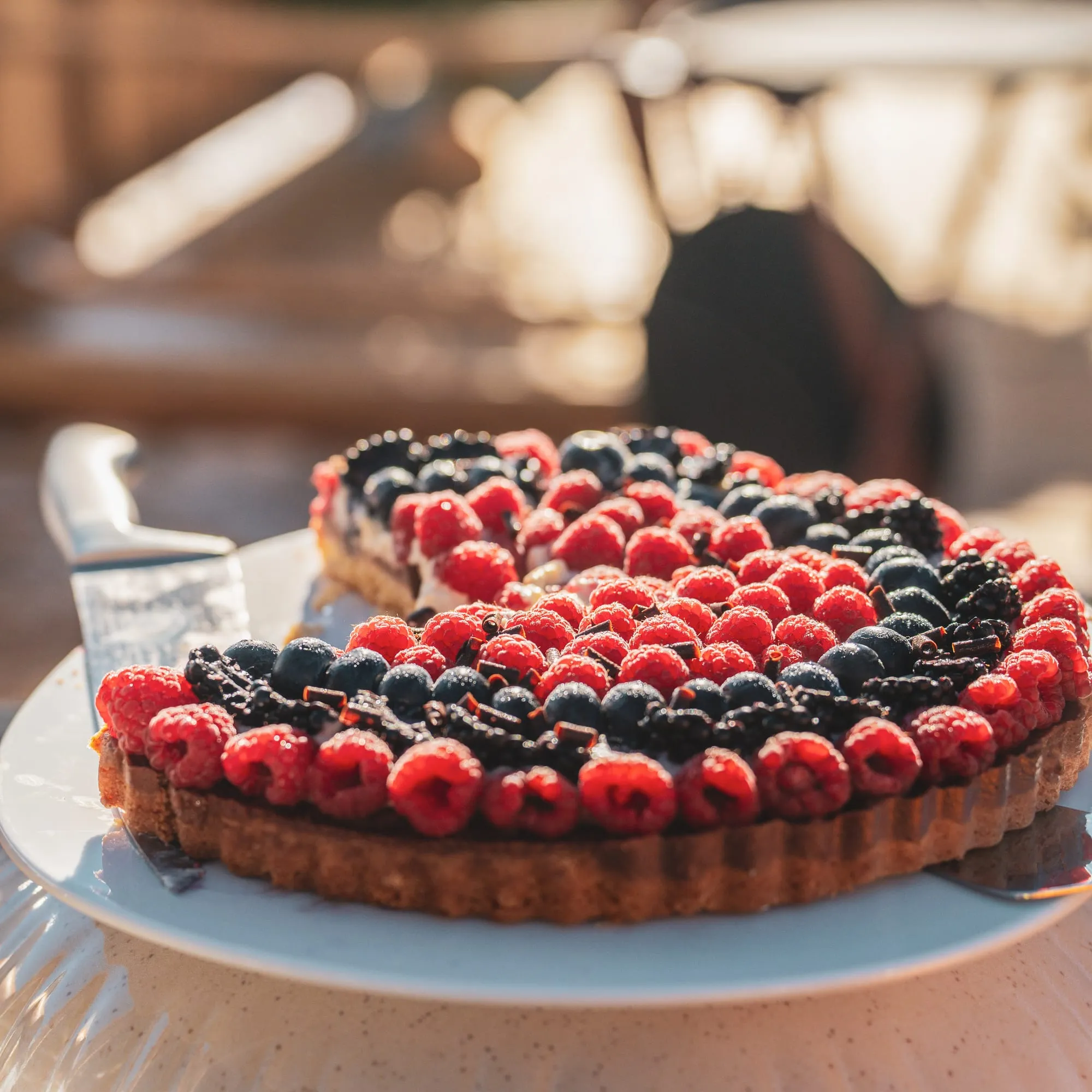 Une tarte aux fruits rouges, framboises et myrtilles, en terrasse.