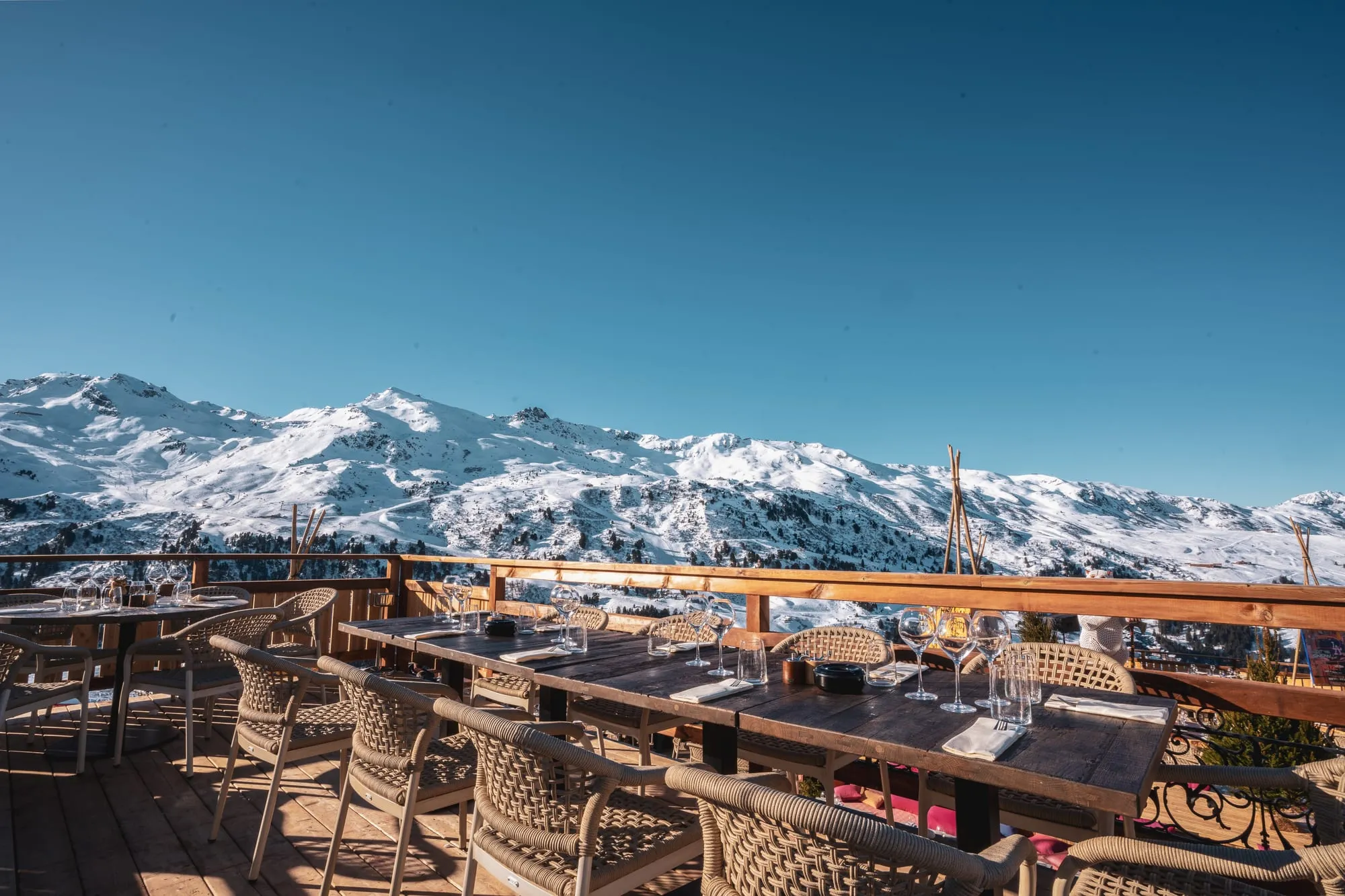 La terrasse de Tipi face aux sommets enneigés, tables dressées sous le grand ciel bleu.