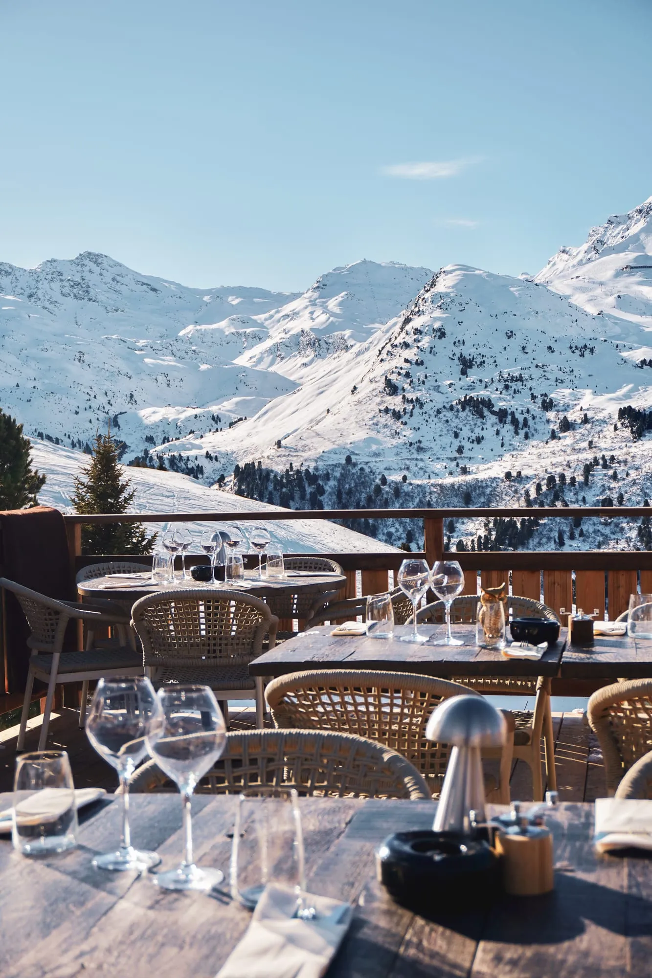 La terrasse de Tipi face aux sommets enneigés, tables dressées au soleil.