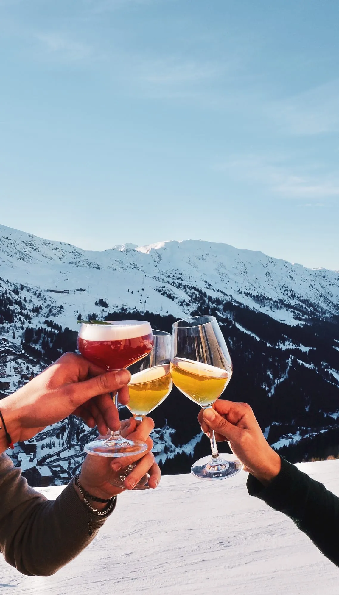 Deux verres qui trinquent devant les montagnes enneigées.